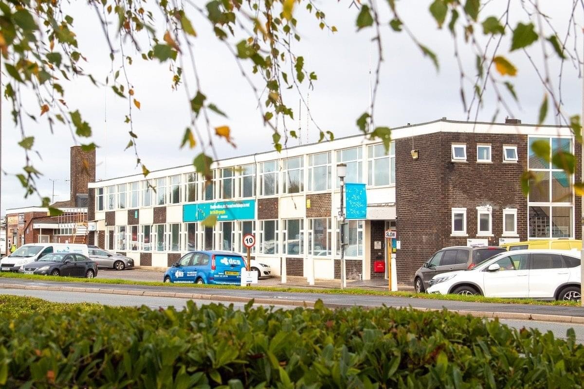 Exterior view of the long, multi-story brick and glass facade of BSS House, Cheney Manor.