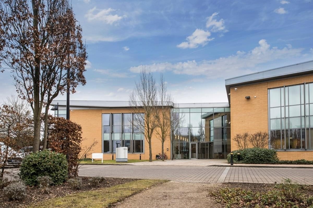 Modern yellow brick facade and glass entrance at Building 1010, Cambourne Business Park.