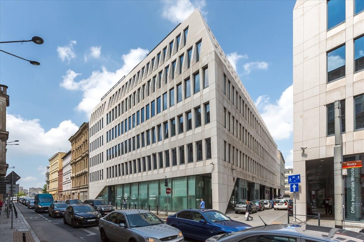 Exterior view of the contemporary white stone and glass Building B, Pegaz on a busy street corner.