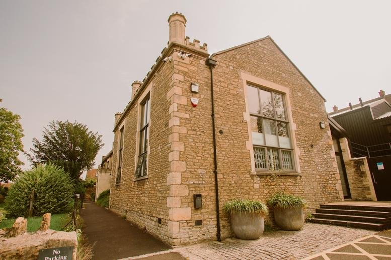 Exterior view of the historic stone facade of The Old Church School with large arched windows.