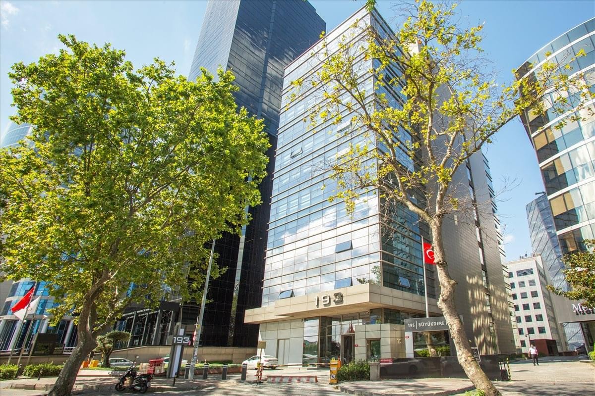 Exterior view of the glass-facade Levent No 193 Binasi surrounded by trees.