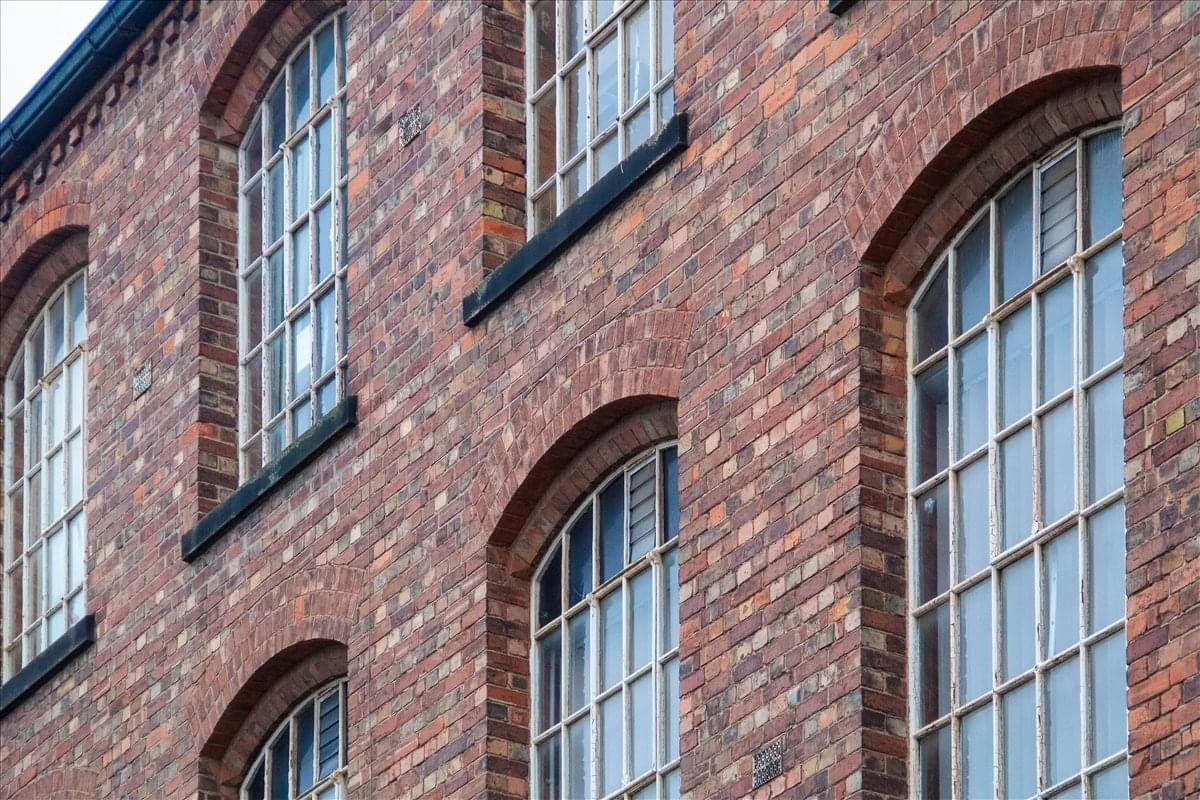 Exterior brick facade of the Byron Industrial Estate featuring large arched industrial windows.