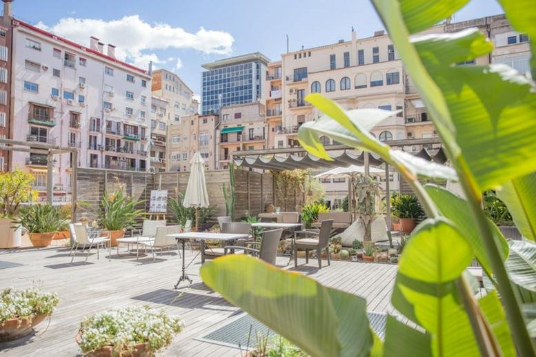 Large rooftop terrace with outdoor furniture and surrounding city architecture.