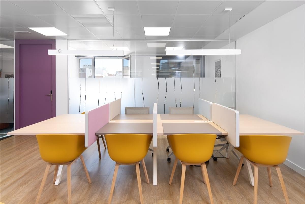Open-plan workspace at Calle de Jose Ortega y Gasset 22-24 with yellow chairs and purple door.