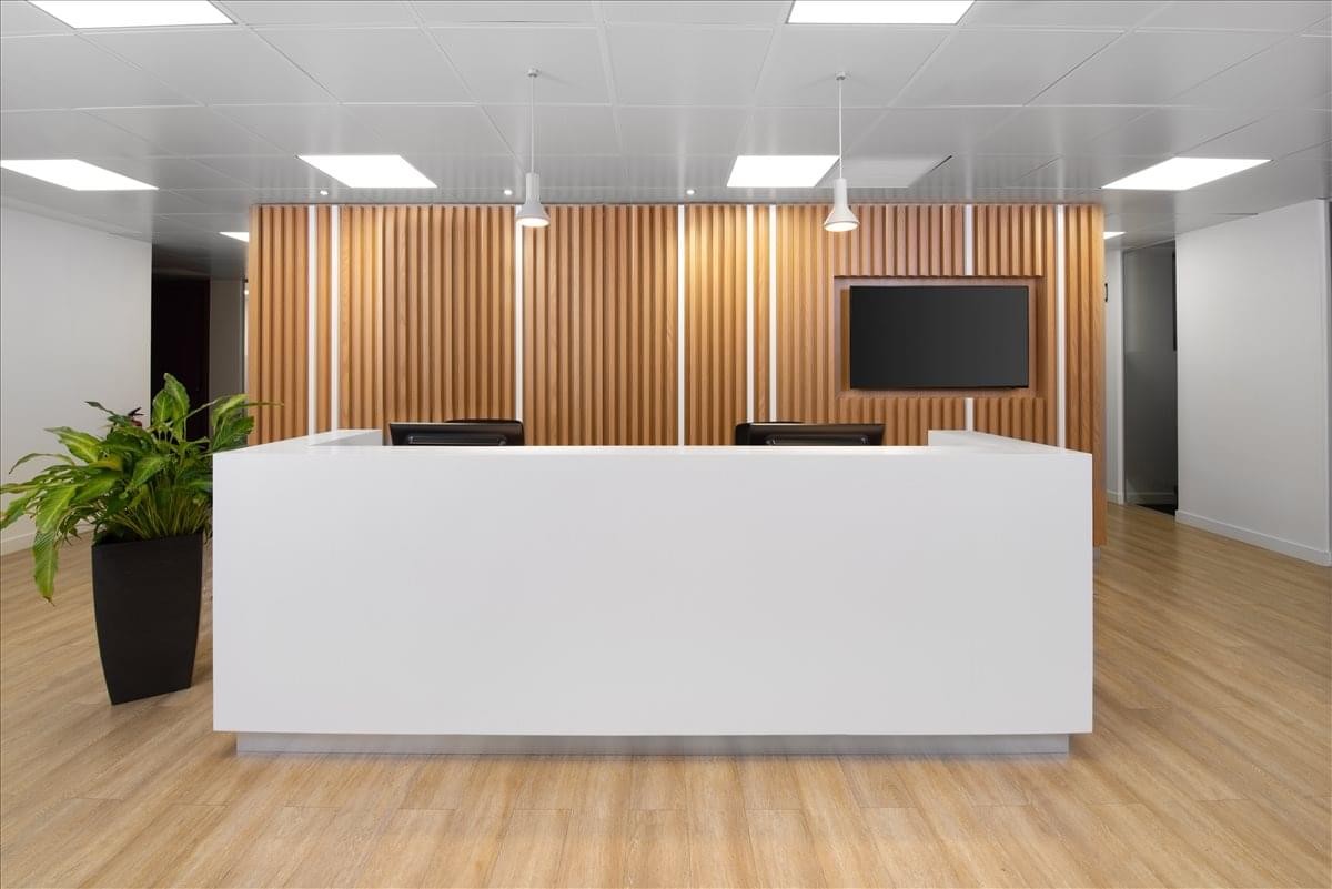 Reception area at Calle de Jose Ortega y Gasset 22-24 with a white desk and wood-slat feature wall.