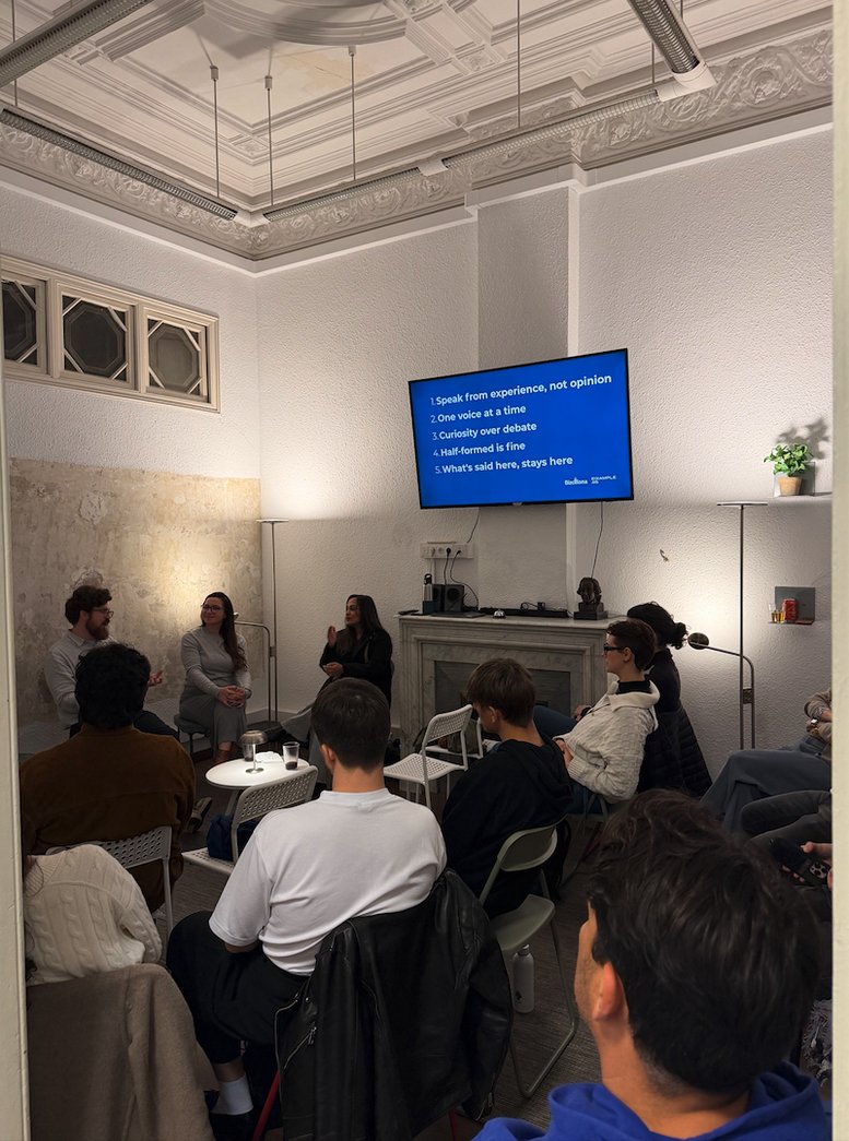 Collaborative presentation room with people seated for a workshop and a screen displaying guidelines.