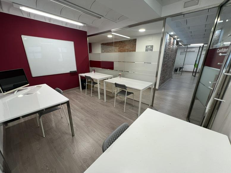 Spacious open-plan workspace at Carrer de Sant Joan Baptista la Salle 6 with white desks and a burgundy feature wall.