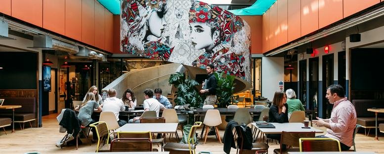 Spacious lobby at Castellana 43 with a large artistic mural and vibrant orange architectural details.