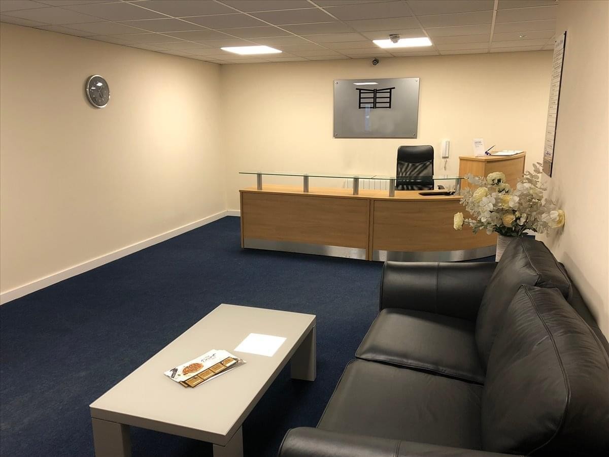 Reception area at Cauldon Locks with a wooden desk, black leather sofa, and blue carpeting.