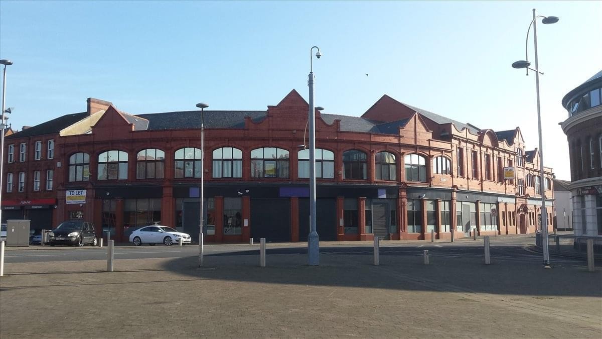 Wide street-level view of the curved red brick building under a clear blue sky.