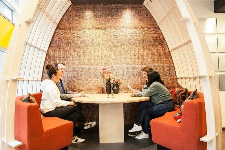 Meeting pod with a curved wooden frame and red seating at Amsterdam south Axis Som 2.