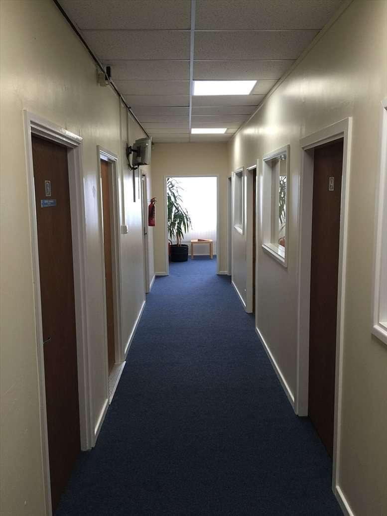 A brightly lit interior corridor at Clayfields Business Centre showing multiple office entrances and blue carpeting.