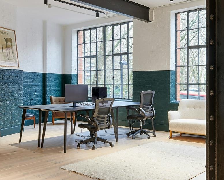 Collaborative office space with shared desks and forest green feature walls.