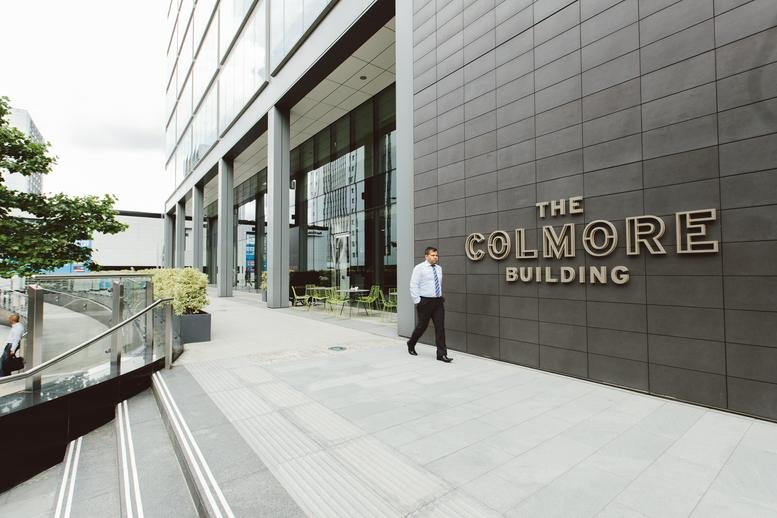 Street-level view of the dark stone facade of The Colmore Building.