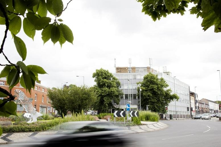 Exterior view of Copthall House, King Street with surrounding trees and a passing car.