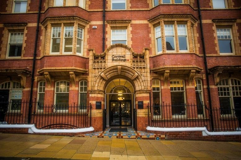 Exterior view of the red brick Cornwall Buildings, 45-51 Newhall Street facade with arched stone entrance.