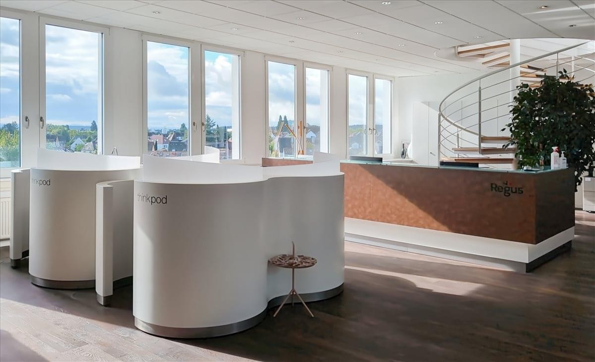 Modern reception area at Curiestraße 2 featuring curved white desks and a wood-paneled counter.