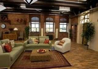 Comfortable communal lounge area with green sofas, brick walls, and large windows.