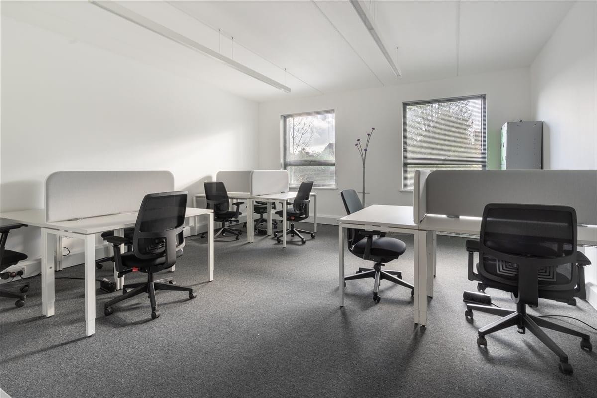 Spacious open-plan workspace at De Mierre House with white desks and black ergonomic chairs.