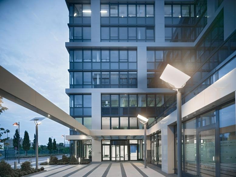Exterior facade and entrance of the modern De-Saint-Exupéry-Str. 10 office building at dusk.