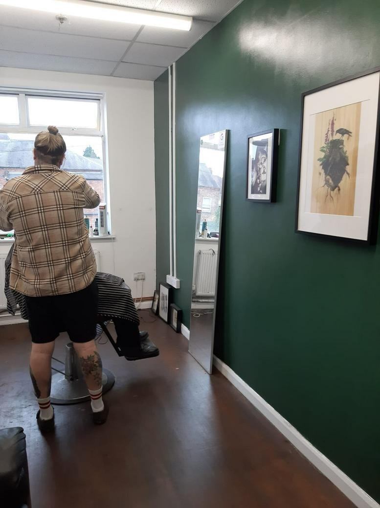 Bright hair salon at Dennis House with a forest green feature wall and decorative mirrors.