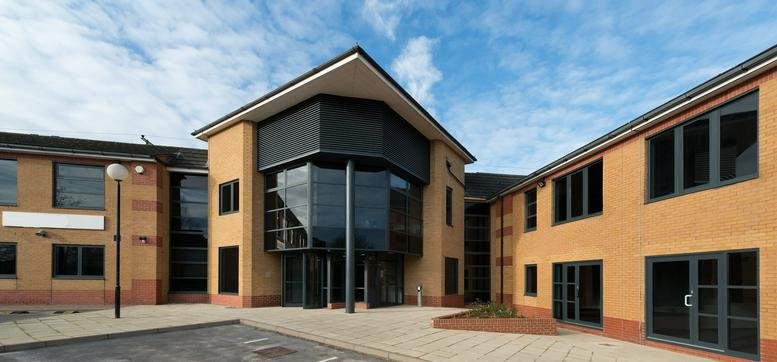 Exterior view of the modern brick facade and glass entrance at Devonshire House, Aviary Court.