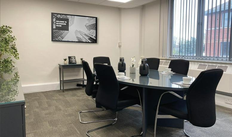 Professional meeting room with a dark oval table and wall art.