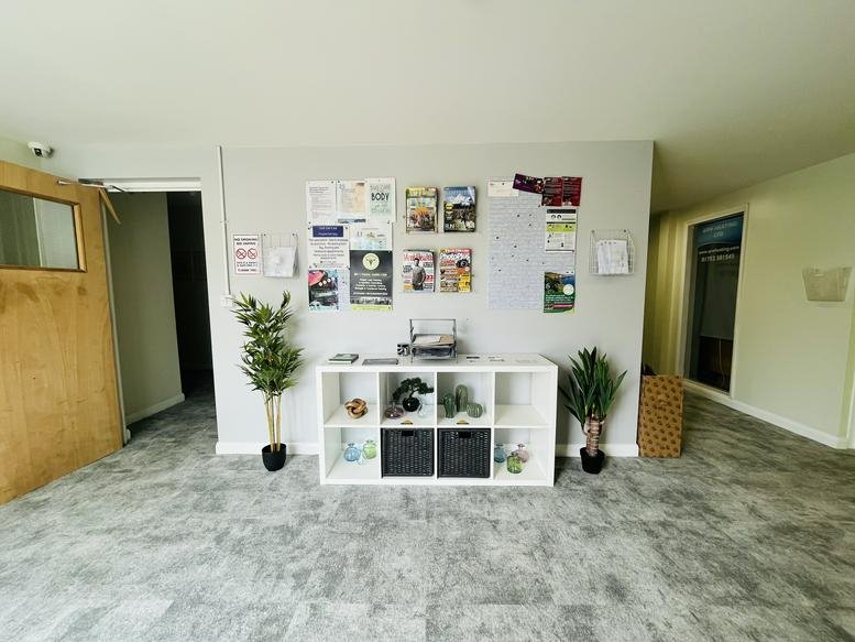 Reception area at Devonshire Meadows with a white shelving unit, plants, and a community notice board.