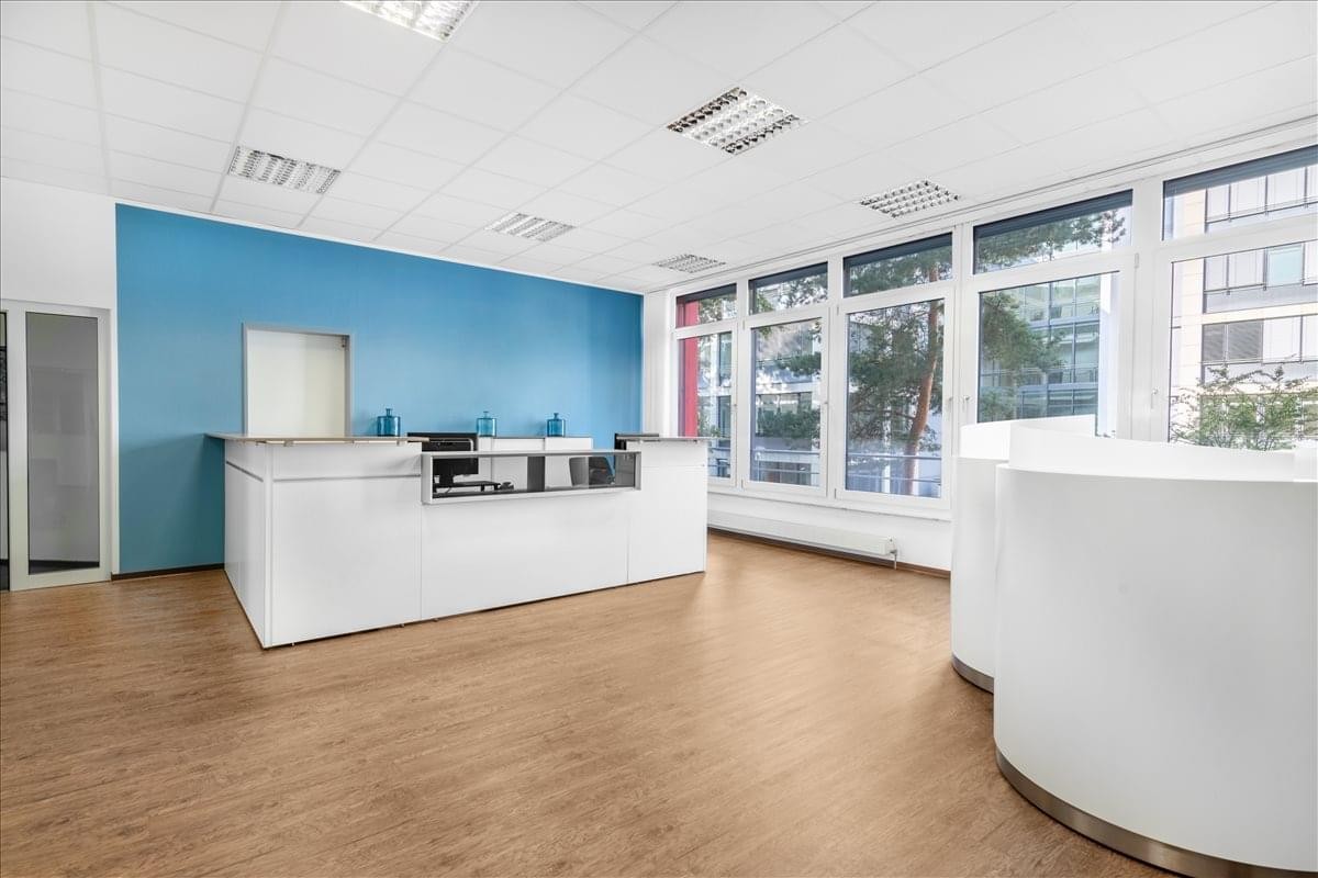 Professional reception area for Dornhofstrasse 34 with a curved white desk and blue feature wall.