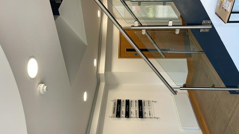 Modern lobby at Premier Gate with a contemporary staircase, glass balustrades, and bright recessed lighting.