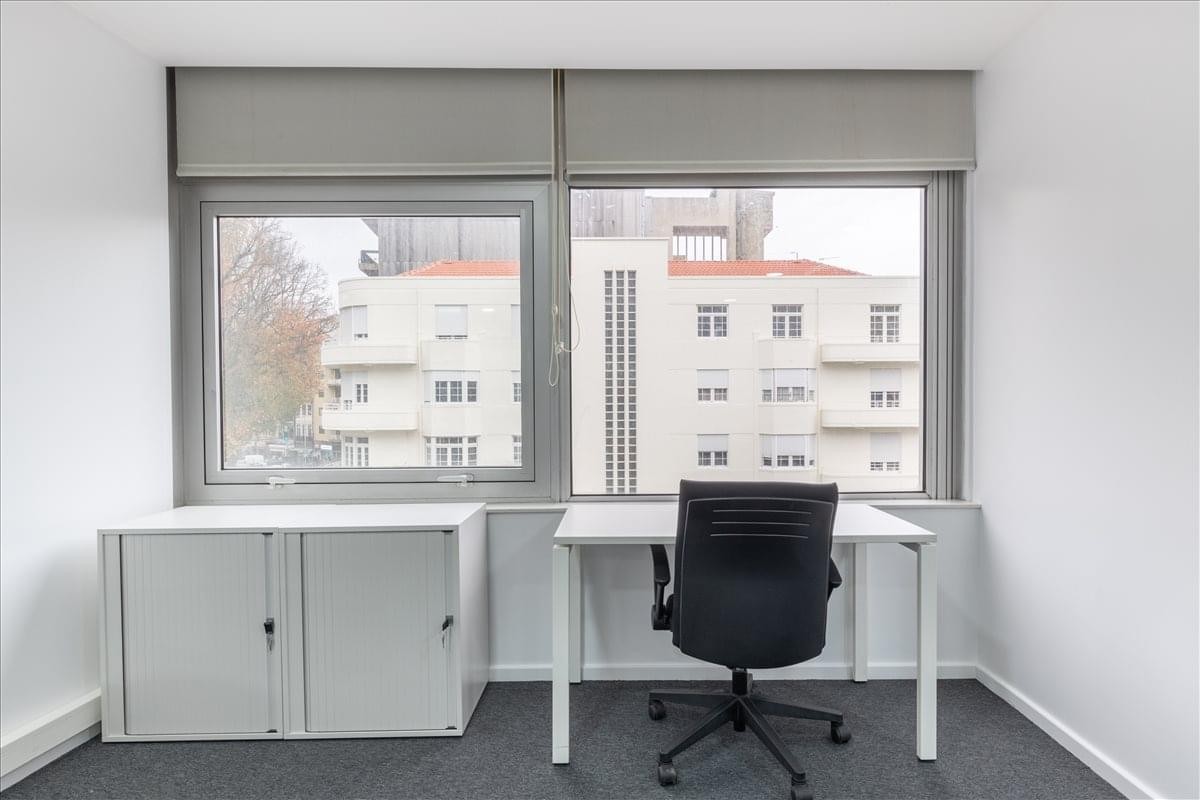 Private office suite with a white desk, grey storage unit, and large window at Edifício Brasília.