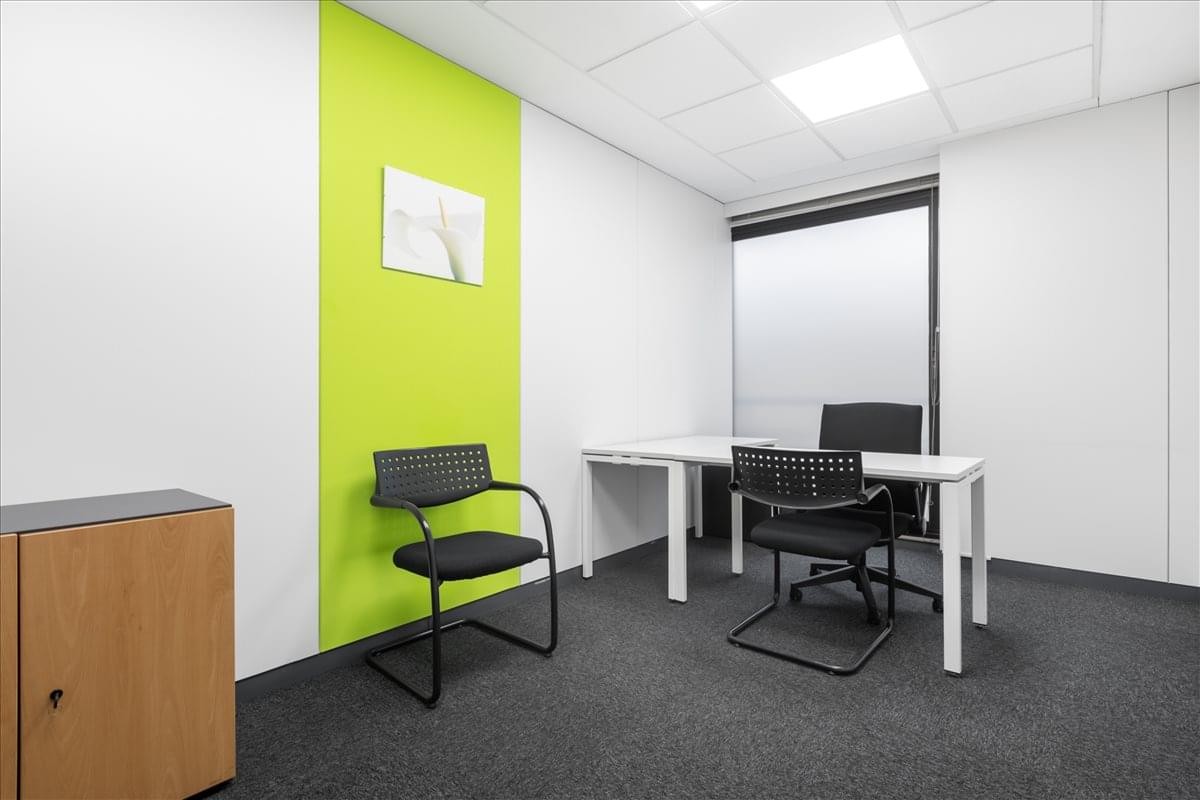 Spacious private office at Edificio Golden featuring a lime green accent wall and professional workstations.