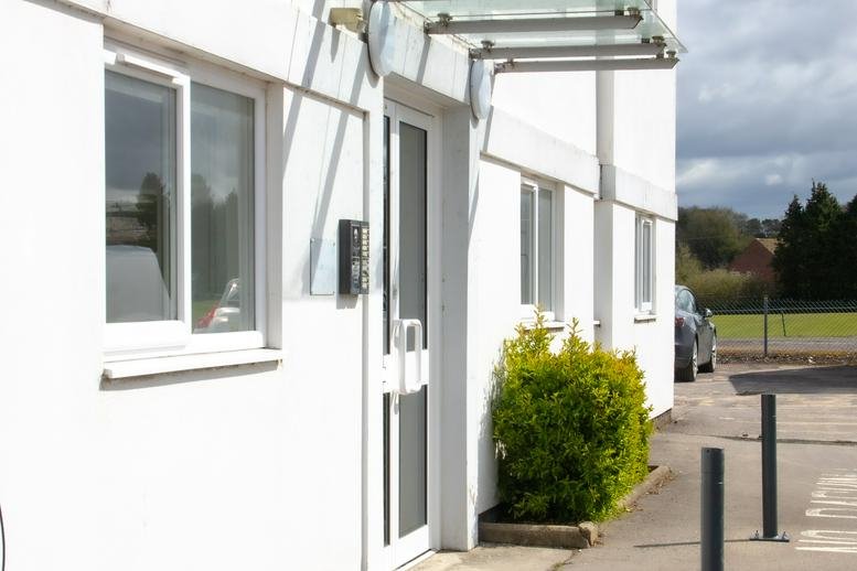 Exterior entrance of Elcot Park, Elcot Lane with white walls and a glass canopy.