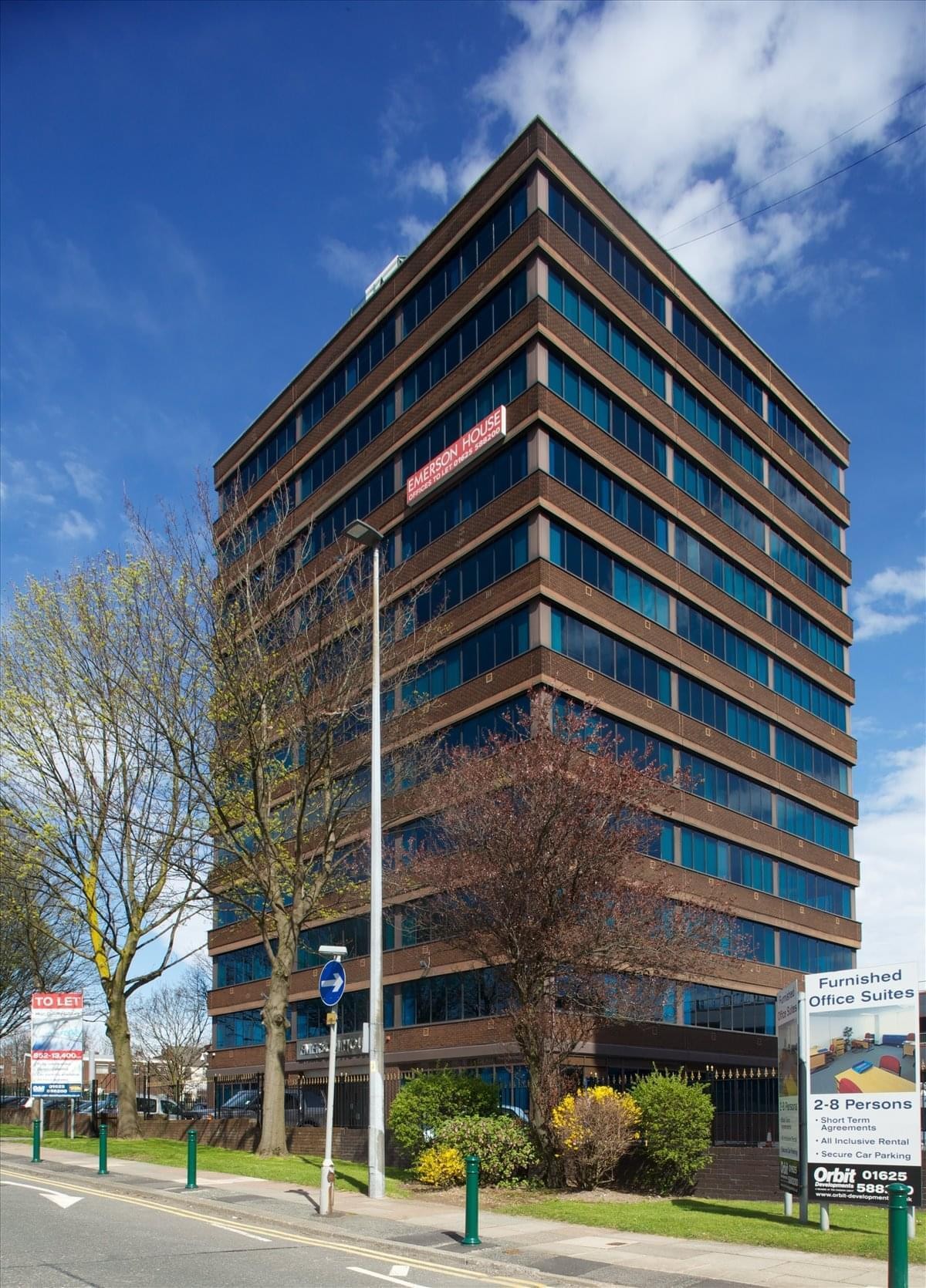 Corner exterior view of the multi-story brown brick office building against a blue sky.