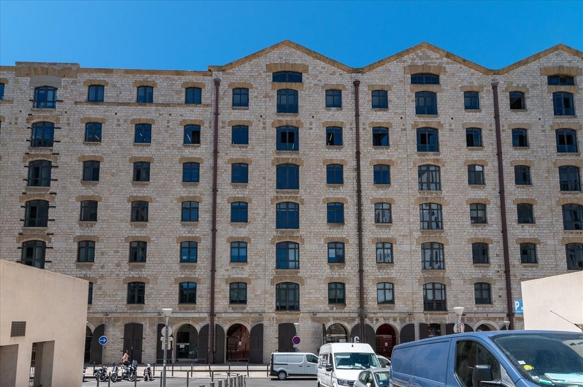 Grand stone facade of the historic Les Docks, Atrium 10. 6 building under a clear blue sky.
