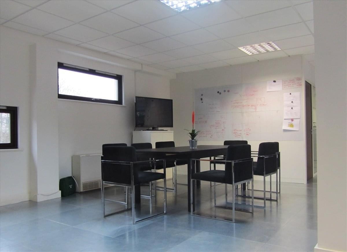 Professional meeting room at Exhibition House, Addison Bridge Place, with a large table, black chairs, and a monitor.