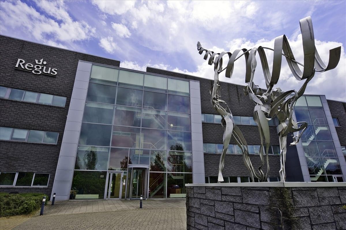 Exterior view of the Fairbourne Drive building with glass entrance and metal ribbon sculpture.