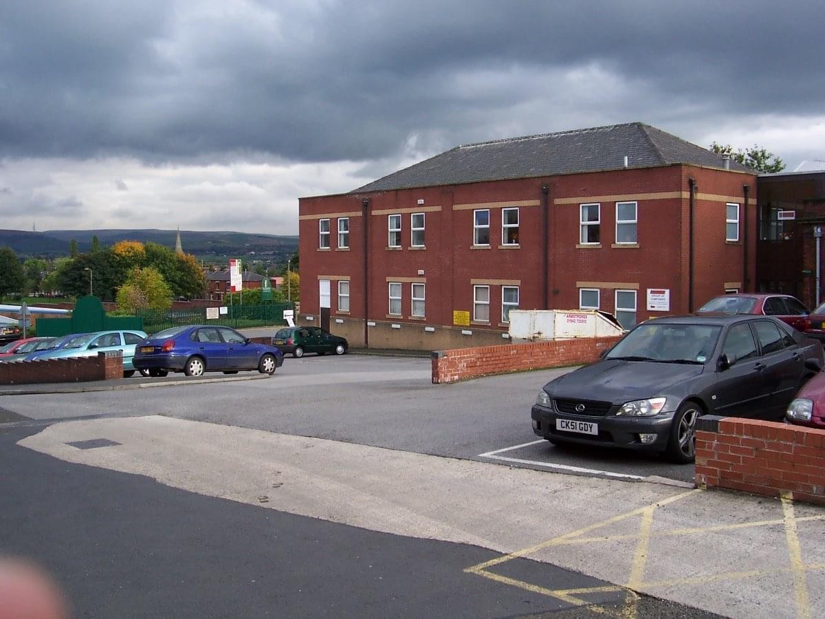 Exterior brick facade of Fieldhouse Industrial Estate, Rochdale, Lancashire with a parking lot in the foreground.