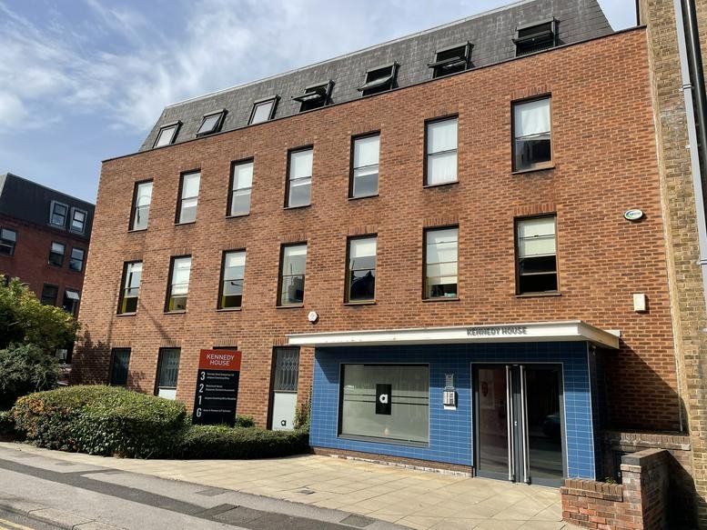 Exterior view of the brick facade at Kennedy House featuring a modern blue entrance and top-floor skylights.