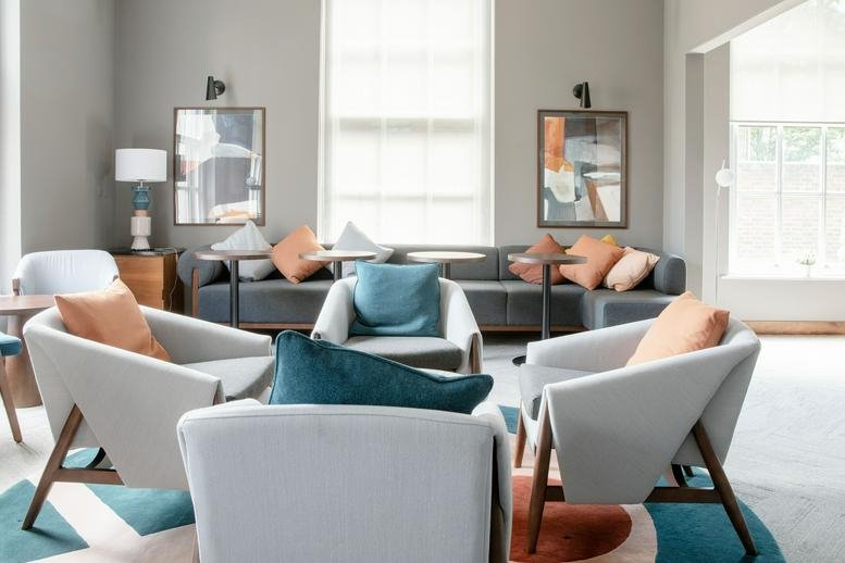 Spacious communal lounge at Fitzwilliam Hall with stylish grey armchairs and colorful rugs.