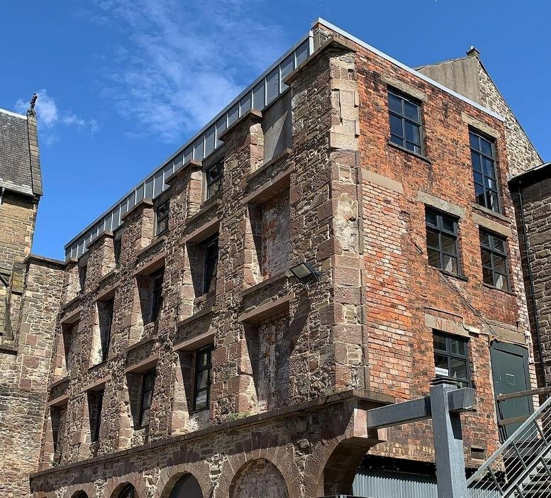 Exterior of the historic red brick and stone Flour Mill building under a bright blue sky.