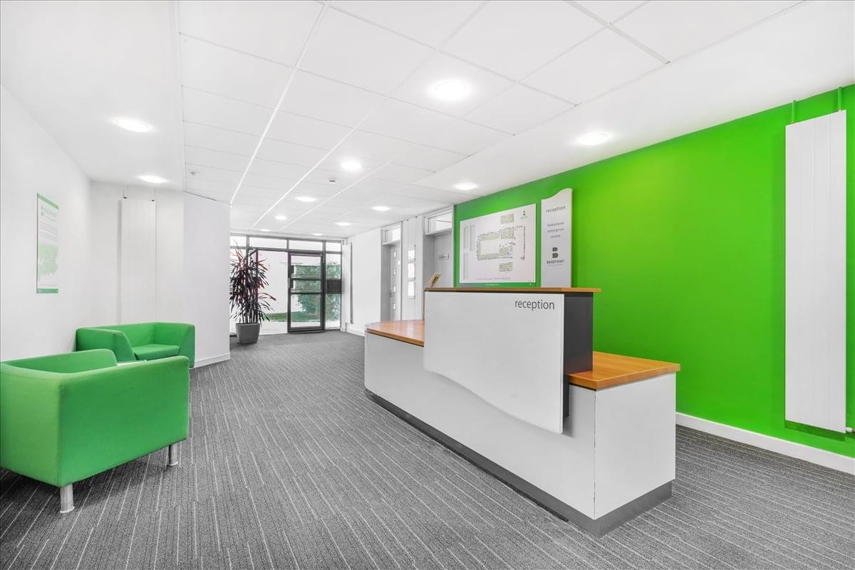 Lobby area featuring a modern reception desk and a bright green feature wall with matching armchairs.