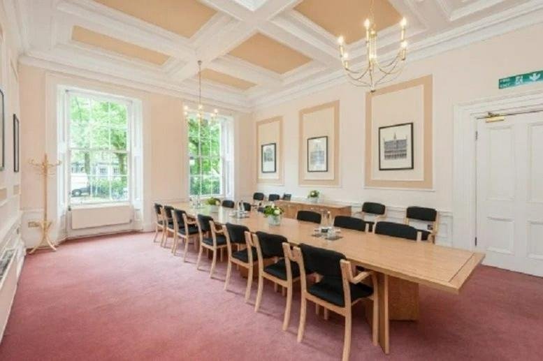 Spacious grand boardroom with ornate ceiling, pink carpet, and large windows.