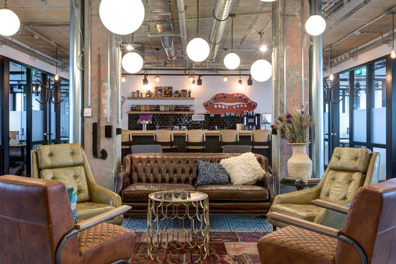 Spacious communal lounge at Friedrichstraße 68 with leather sofas and orb pendant lighting.