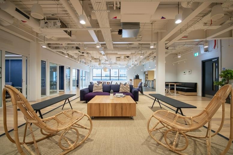 Spacious communal lounge at Shoreditch Exchange with wicker rocking chairs and wooden coffee table.