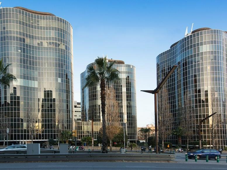 Exterior view of the curved glass-facade towers at Gran Vía de Carles III, 84 3rd and 4th floors.