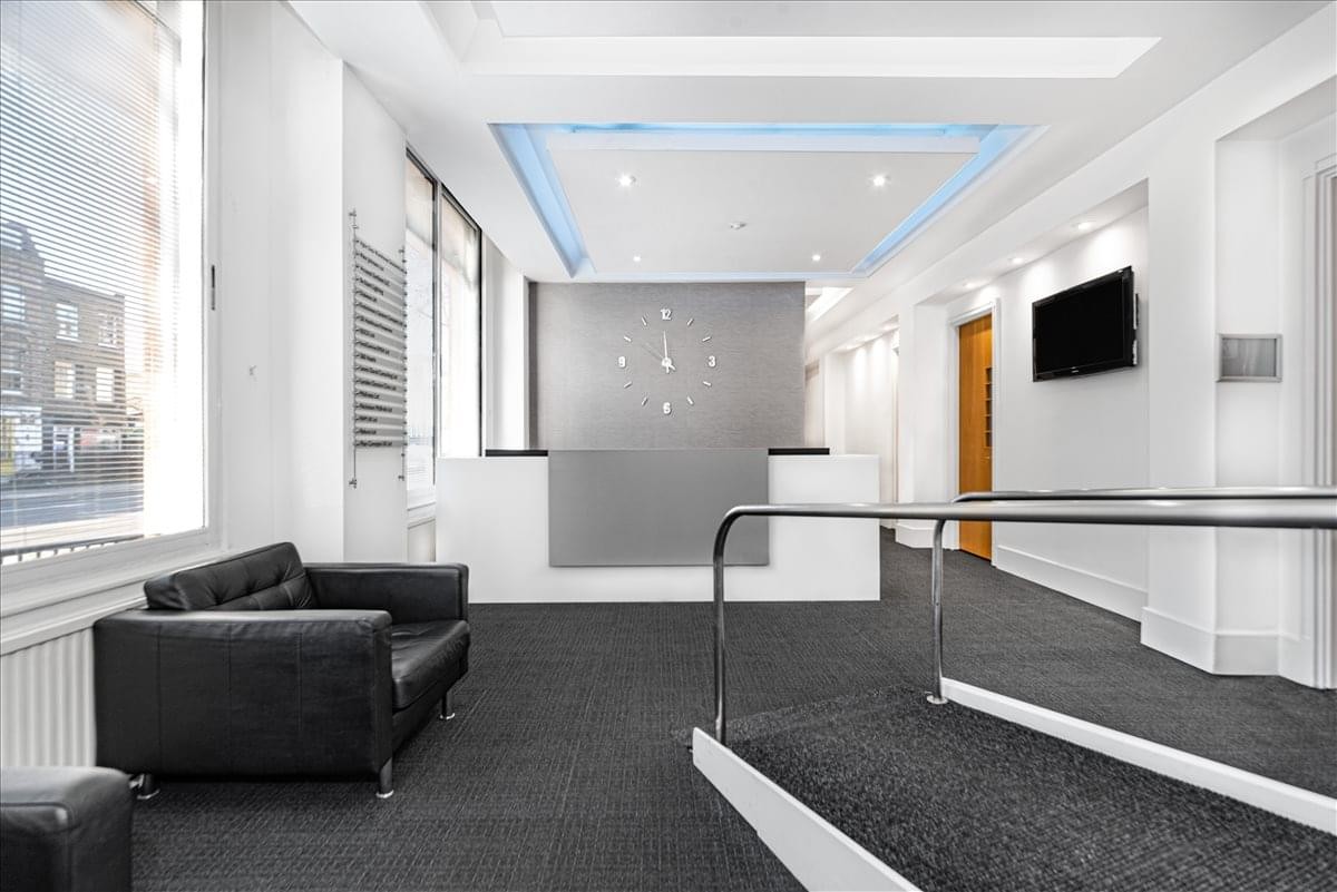 Minimalist reception area with a grey feature wall, leather sofa, and modern lighting.