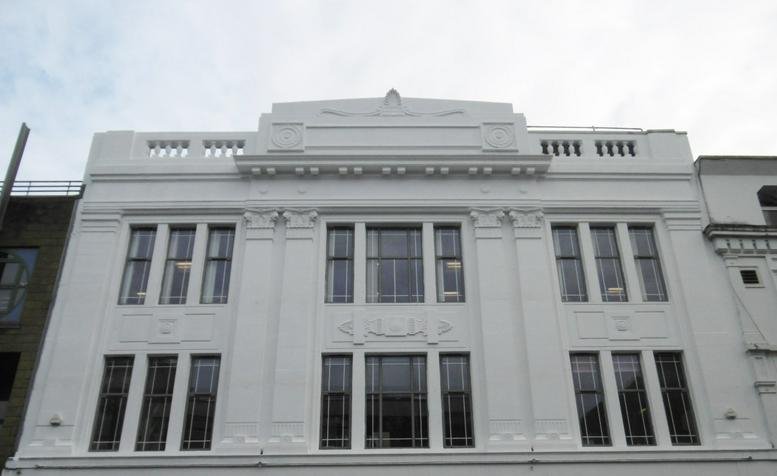 Exterior facade of the white stone Green Fish Resource Centre with tiered architectural detailing.