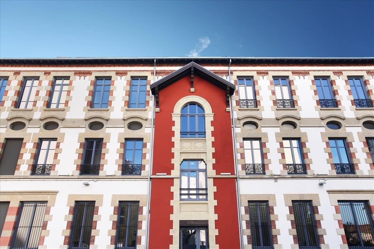 Exterior facade of the historic Grenoble City, 155-157 cours Berriat building with red and white stone.