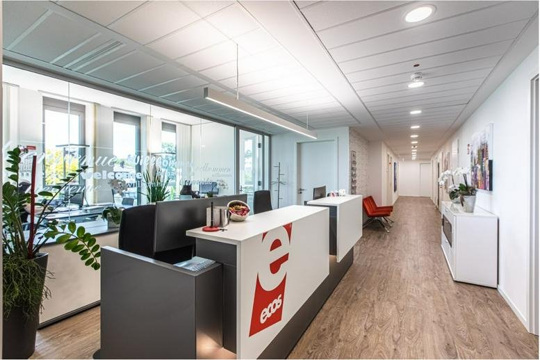 Bright reception area of Gustav-Stresemann-Ring 1 with a branded front desk and wooden flooring.